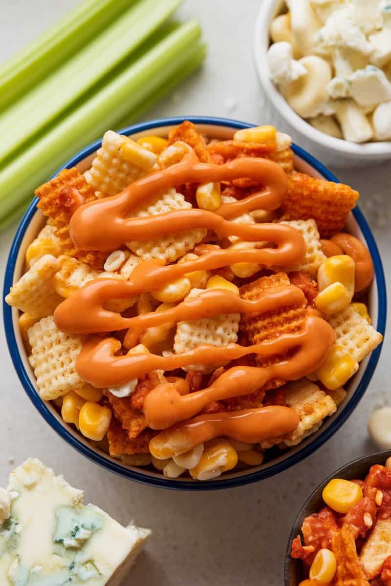 A bowl of Buffalo Wing Chex Mix with crunchy cereal, pretzels, and drizzled sauce.