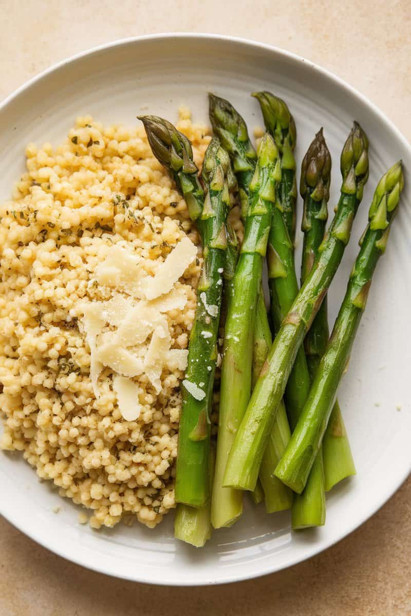 A plate of garlic and herb couscous served with asparagus.