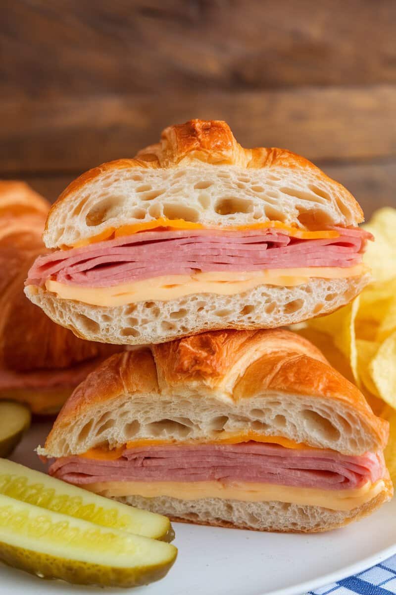 A delicious ham and cheese croissant sandwich cut in half, showcasing layers of ham and cheese.