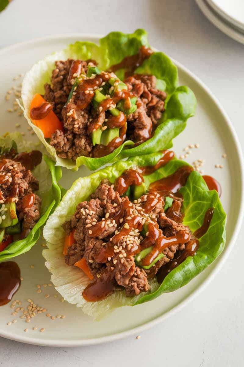 Delicious Impossible Beef Lettuce Wraps filled with plant-based beef and colorful veggies, drizzled with sauce.