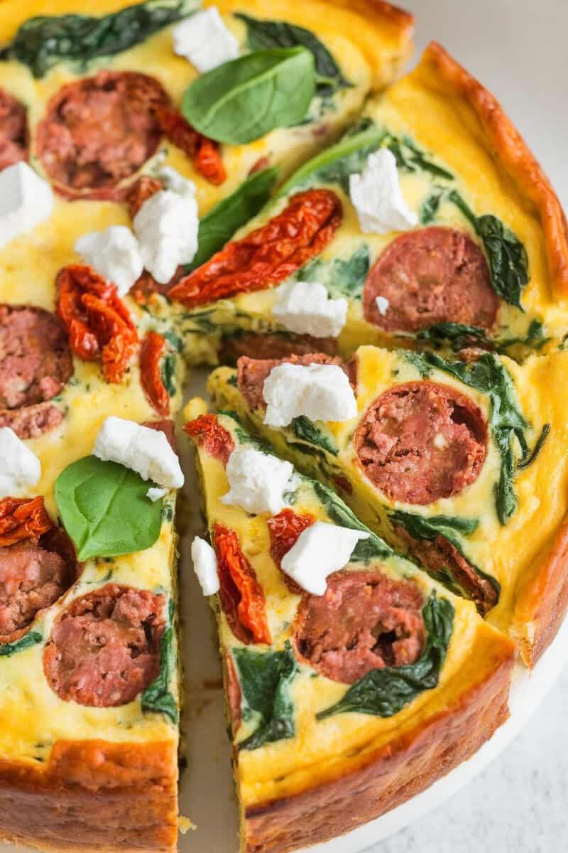 A sliced Mediterranean frittata with sausage, spinach, sun-dried tomatoes, and feta cheese.