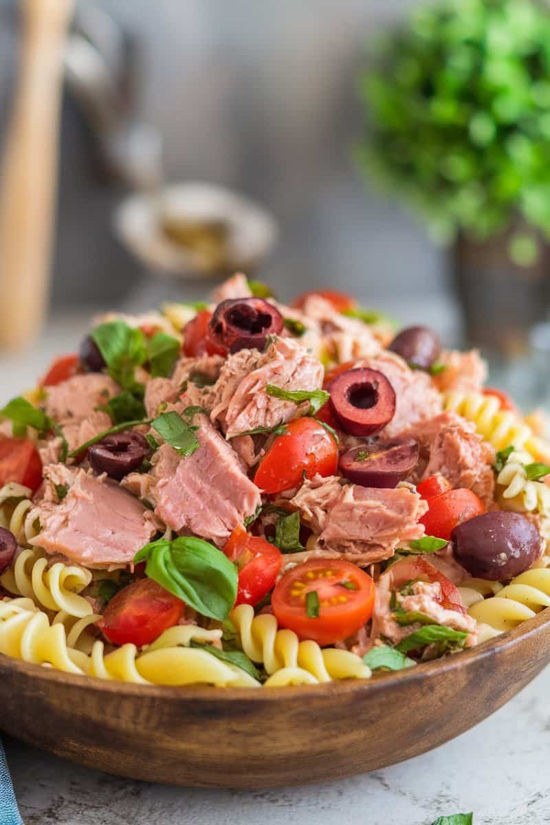 A colorful Mediterranean Tuna Pasta Salad with rotini, tuna, cherry tomatoes, olives, and fresh basil.