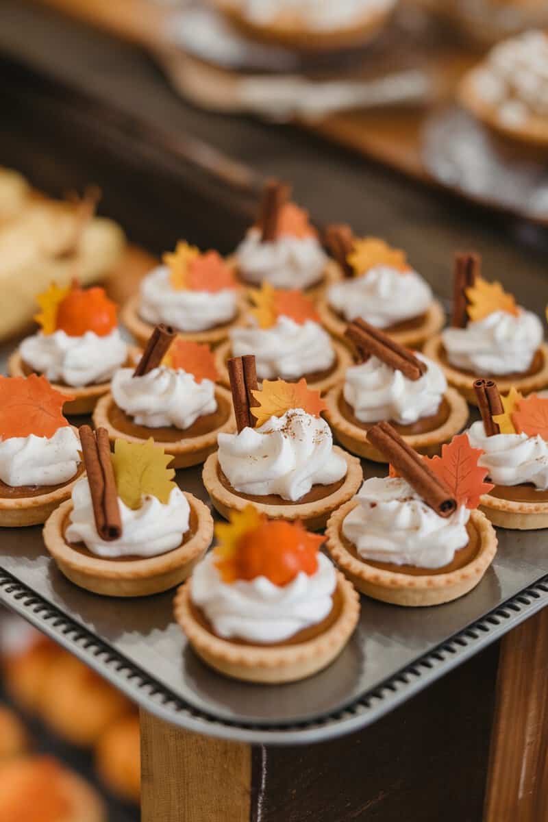 Mini pumpkin pies topped with whipped cream and autumn decorations