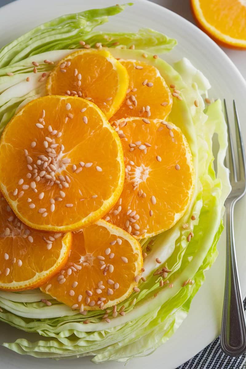 Napa cabbage salad topped with orange slices and sesame seeds.