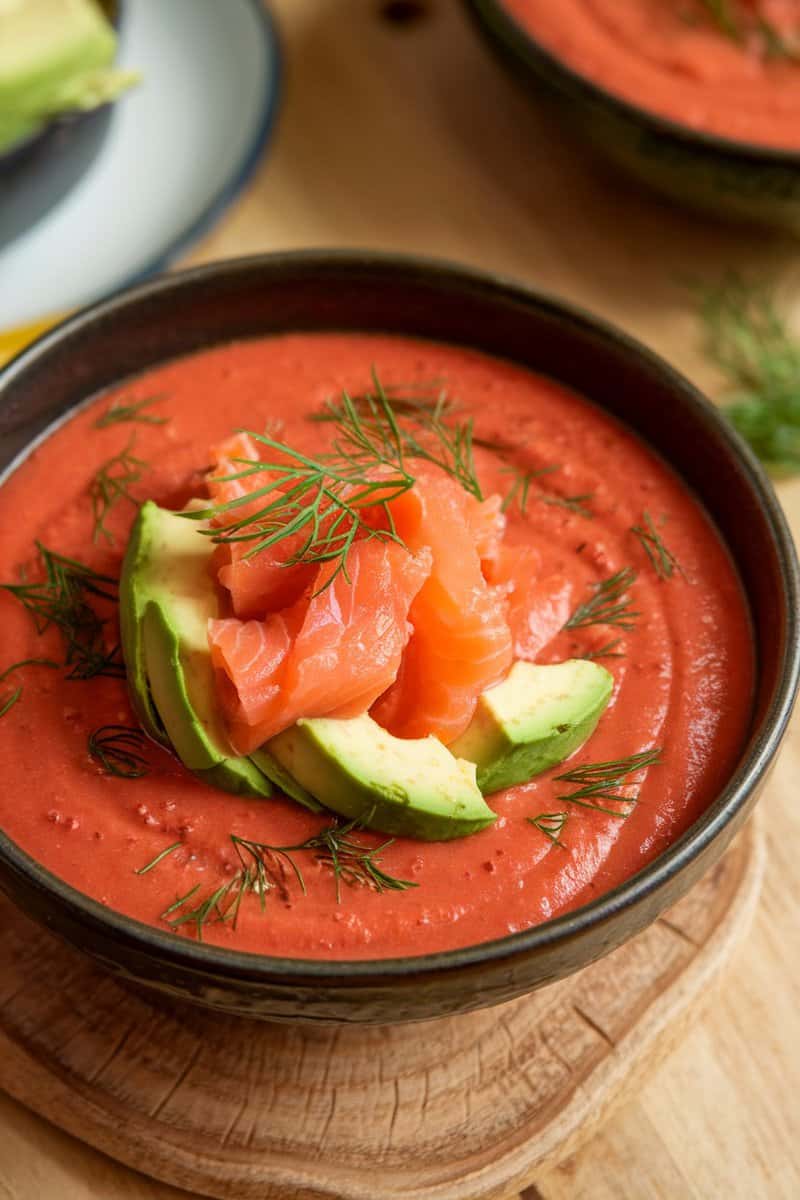 A bowl of smoked salmon and avocado gazpacho topped with diced avocado and salmon.