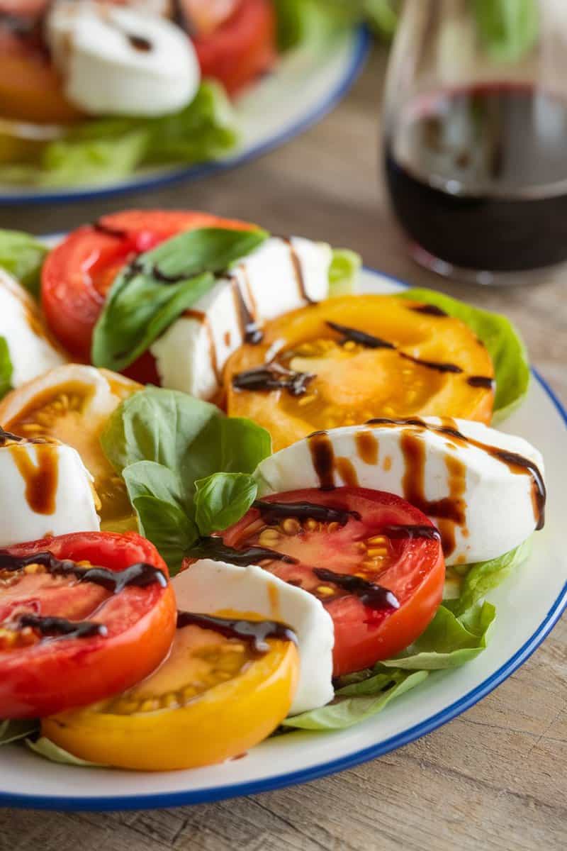 A vibrant roasted yellow tomato caprese salad with mozzarella and basil.