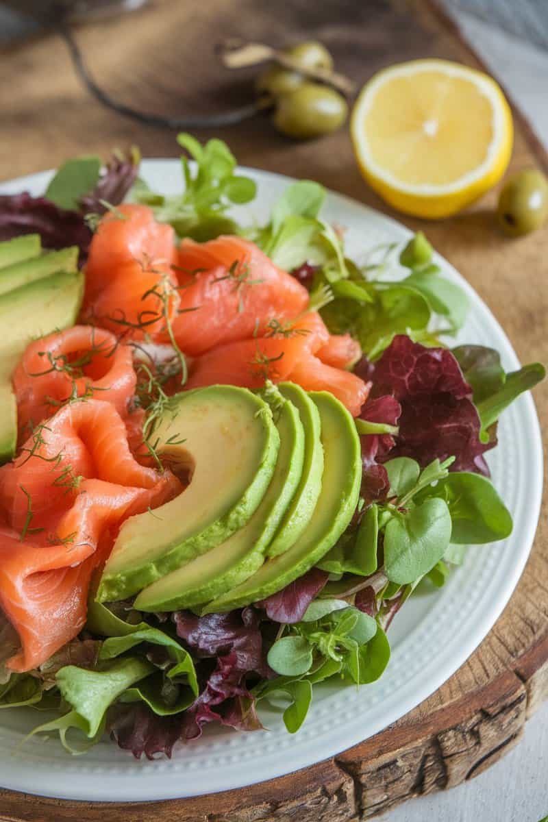 A vibrant smoked salmon and avocado salad on a plate, garnished with fresh greens.