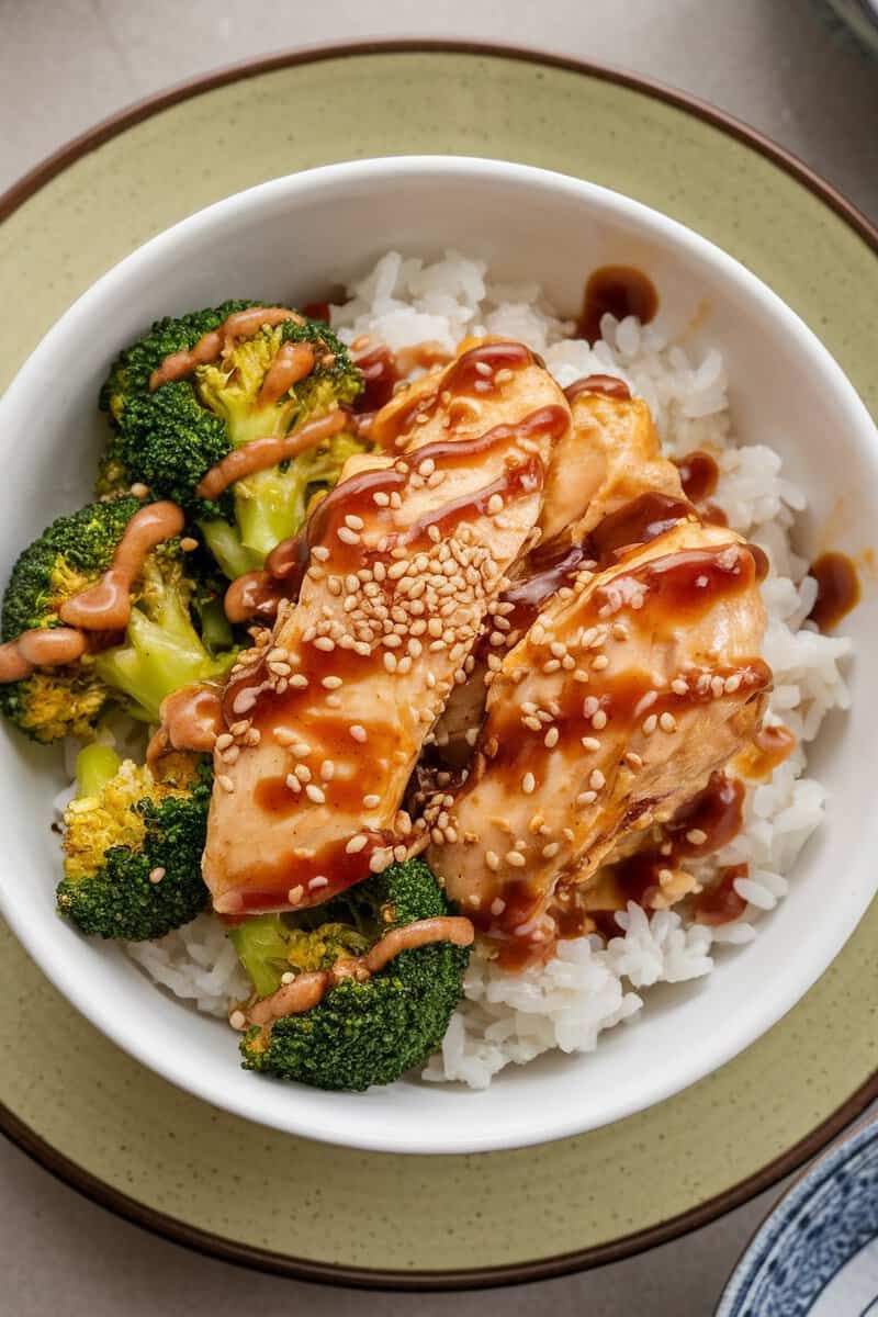 A bowl of sesame chicken with broccoli and rice.