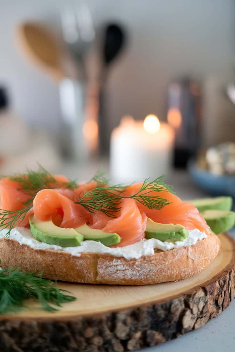 A flatbread topped with cream cheese, smoked salmon, avocado slices, and fresh dill.