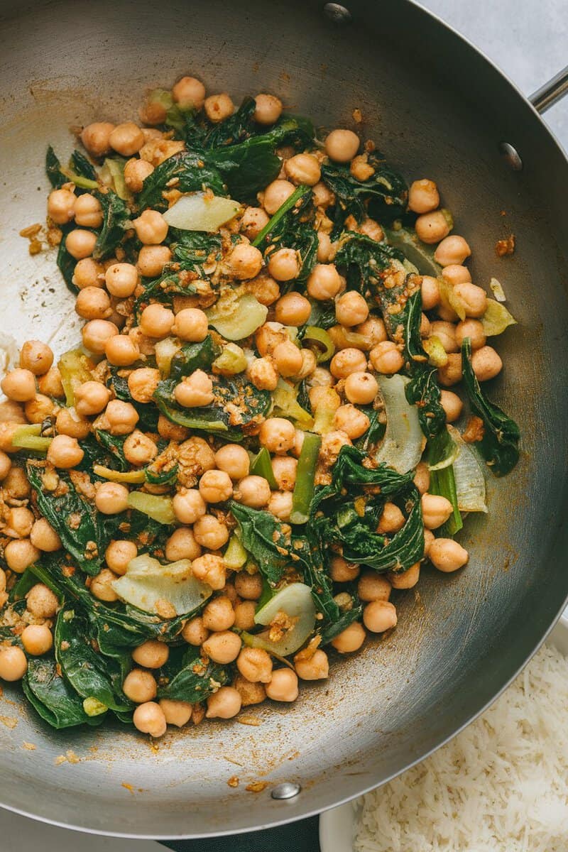 A pan of spicy chickpea and spinach stir-fry with chickpeas, spinach, and spices