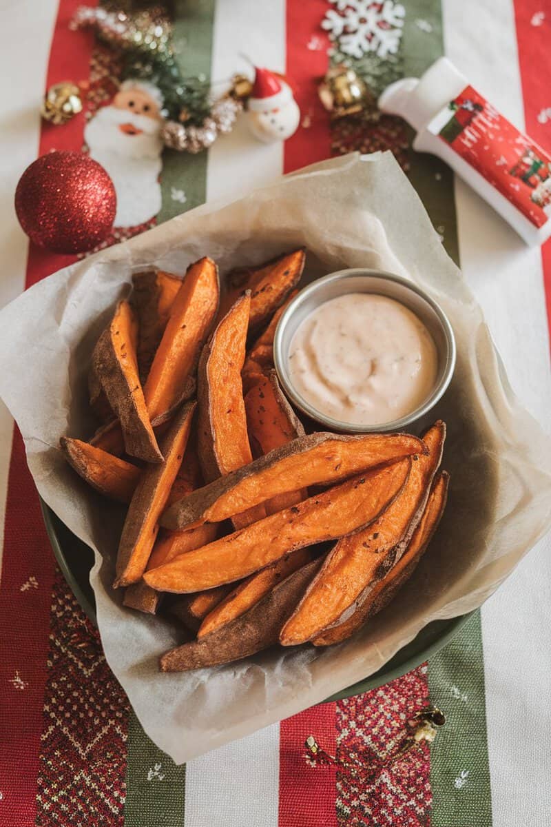 Delicious spicy sweet potato wedges with a creamy dipping sauce, set against a festive Christmas table.