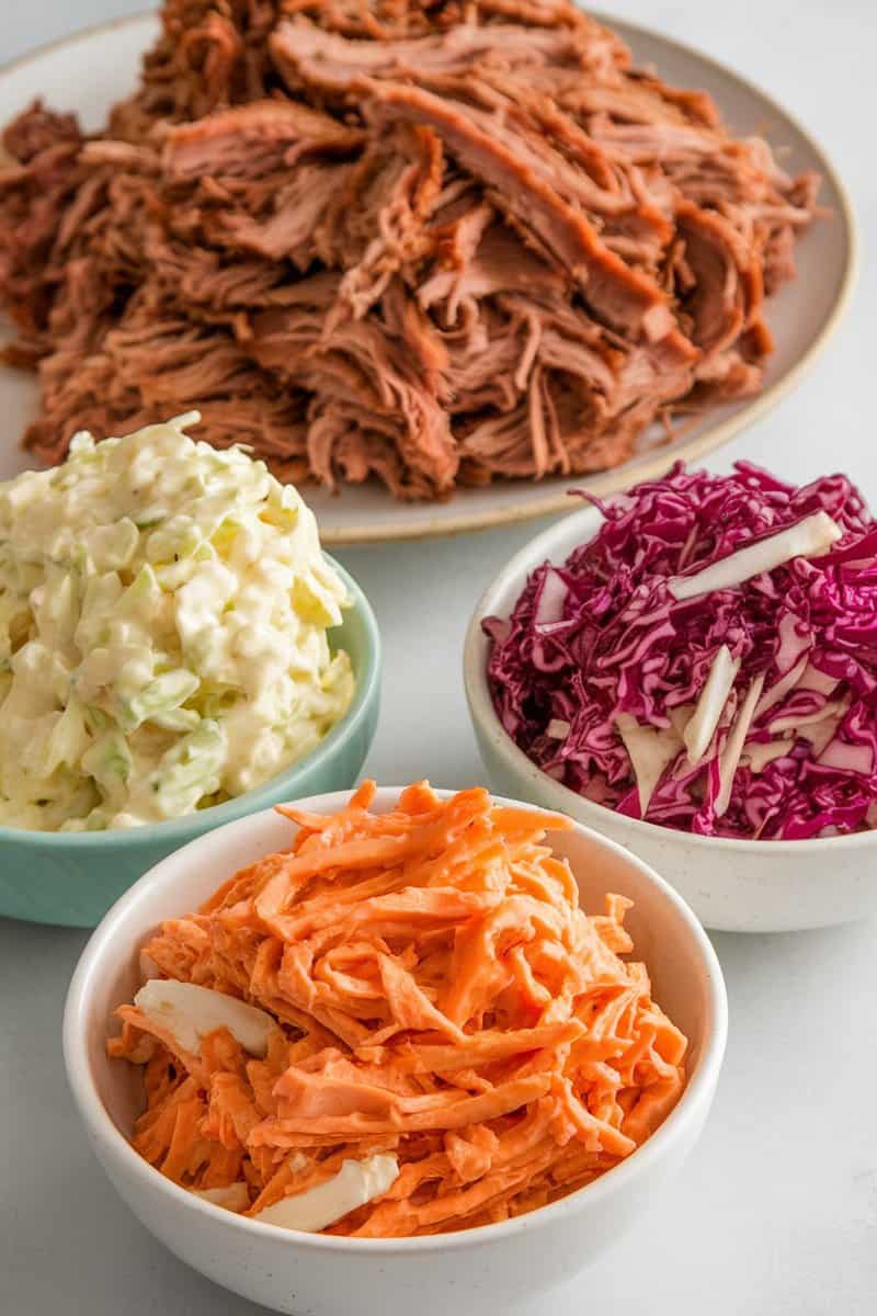 A colorful display of coleslaw varieties with shredded green and red cabbage, and carrots.