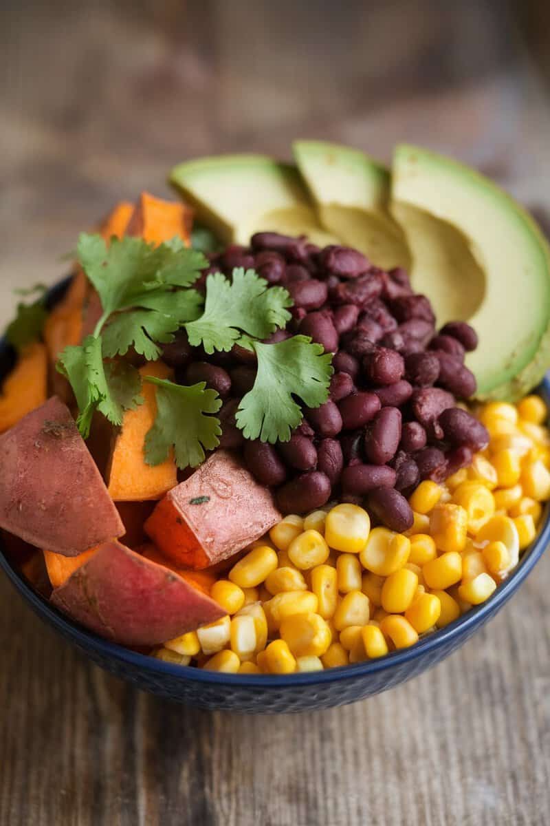 A healthy sweet potato and black bean bowl with corn, avocado, and cilantro.