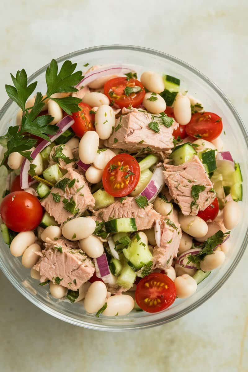 A vibrant bowl of Tuna and White Bean Salad with cherry tomatoes, cucumbers, and red onion.