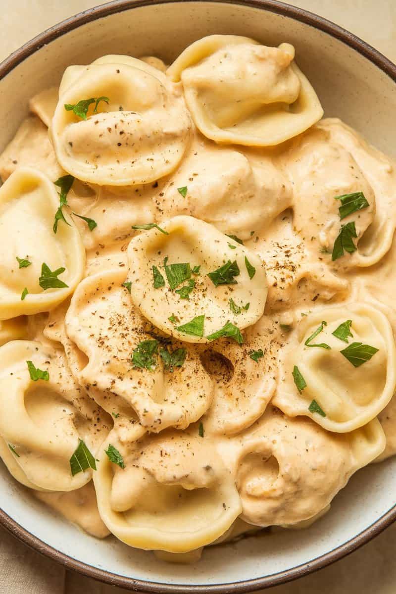 A bowl of Chicken Tortellini Alfredo topped with parsley